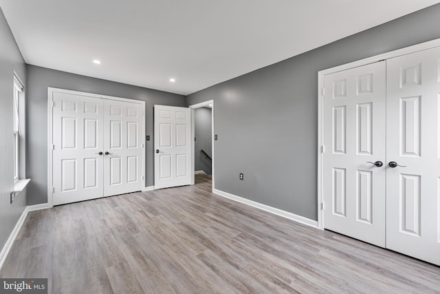 unfurnished bedroom featuring light wood-type flooring and multiple closets