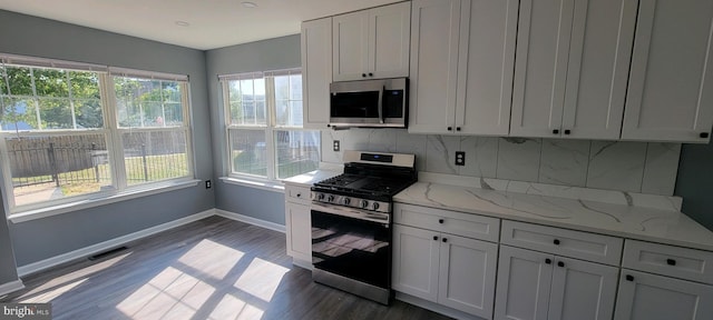 kitchen featuring light stone countertops, appliances with stainless steel finishes, plenty of natural light, and dark wood-type flooring