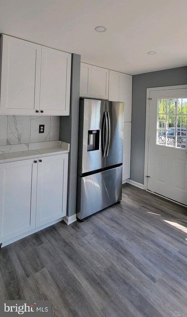 kitchen with white cabinets, tasteful backsplash, dark wood-type flooring, and stainless steel fridge