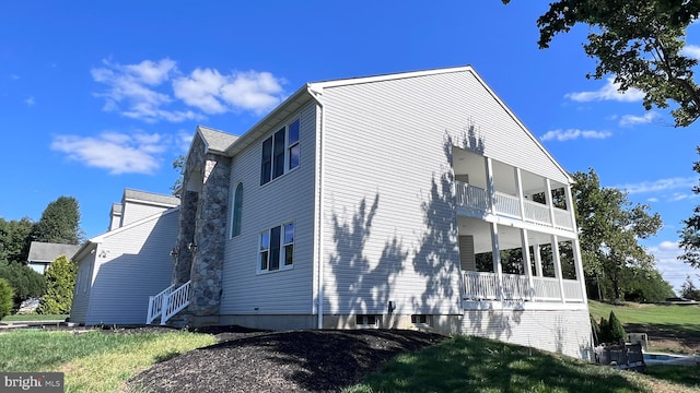 view of home's exterior featuring a balcony and a yard