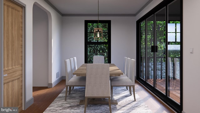 dining space with arched walkways, ornamental molding, wood finished floors, and baseboards