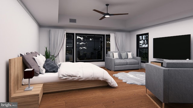 bedroom featuring a ceiling fan, a tray ceiling, visible vents, and wood finished floors