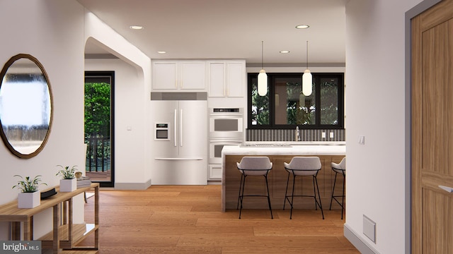 kitchen featuring built in refrigerator, light wood finished floors, double oven, and white cabinets