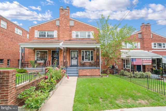 view of front of house with a front yard, fence, brick siding, and covered porch