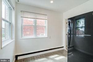 empty room featuring baseboard heating and plenty of natural light