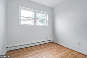 empty room with a baseboard radiator and light hardwood / wood-style flooring