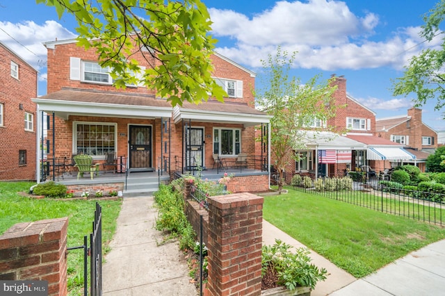 view of front facade featuring brick siding, a front lawn, fence, and covered porch