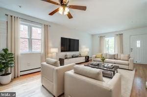 living room featuring a baseboard heating unit, ceiling fan, and light wood-type flooring