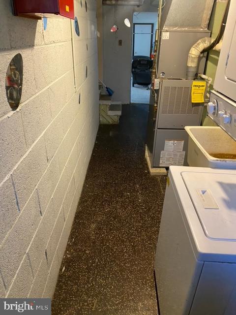 laundry room featuring heating unit and stacked washer and dryer