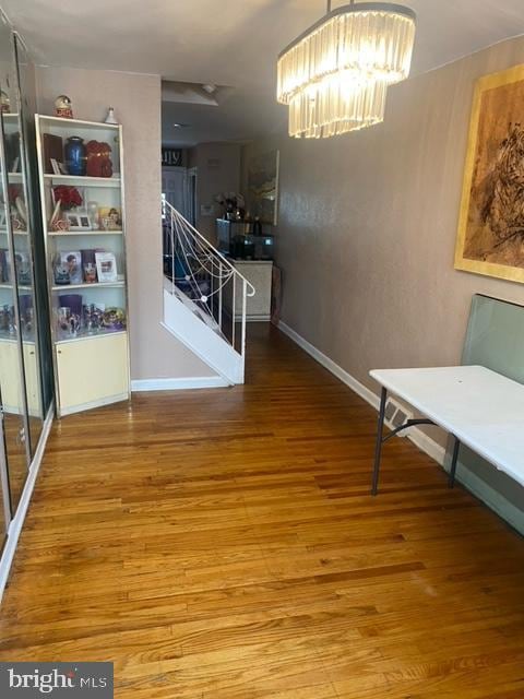 hallway featuring wood-type flooring and an inviting chandelier