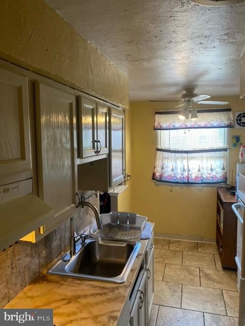 kitchen featuring a textured ceiling, ceiling fan, light tile patterned floors, and sink