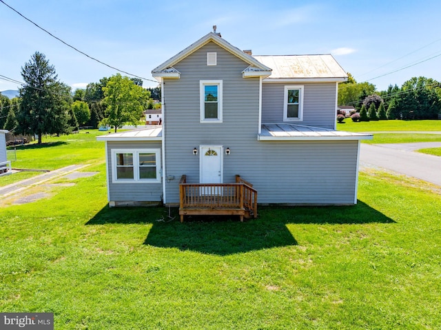 back of property featuring metal roof, a standing seam roof, a chimney, and a lawn