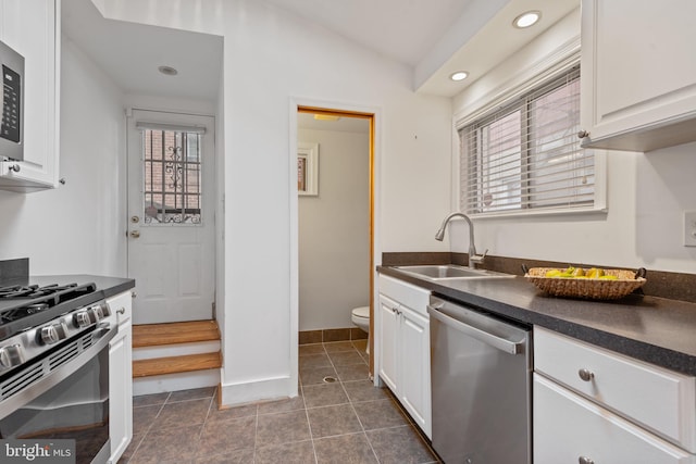 kitchen with lofted ceiling, stainless steel appliances, sink, and white cabinetry