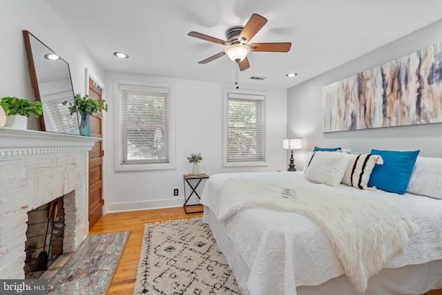 bedroom featuring ceiling fan, light wood-type flooring, and a fireplace