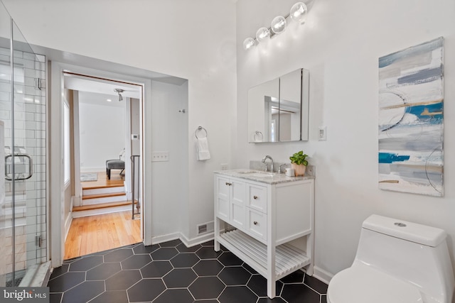 bathroom featuring toilet, hardwood / wood-style flooring, a shower with door, and vanity