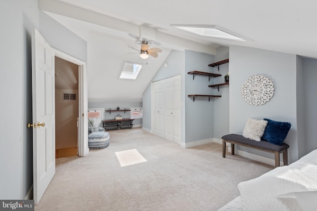 bedroom with light carpet, vaulted ceiling with skylight, ceiling fan, and a closet