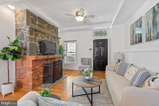 living room featuring a fireplace, light wood-type flooring, and ceiling fan