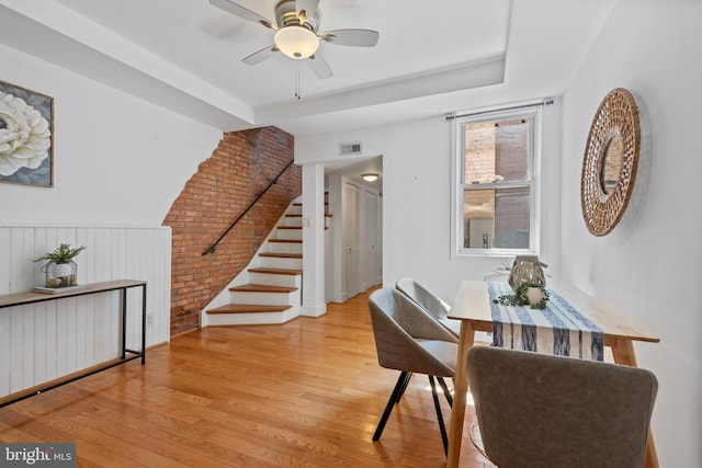 dining space featuring brick wall, ceiling fan, and light hardwood / wood-style floors