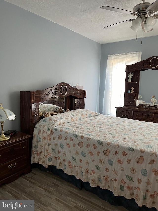 bedroom with dark hardwood / wood-style floors, ceiling fan, and a textured ceiling