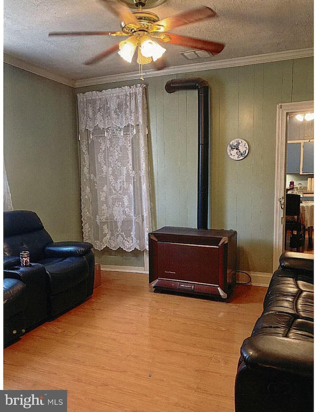 living room with wood-type flooring, a textured ceiling, ceiling fan, and crown molding