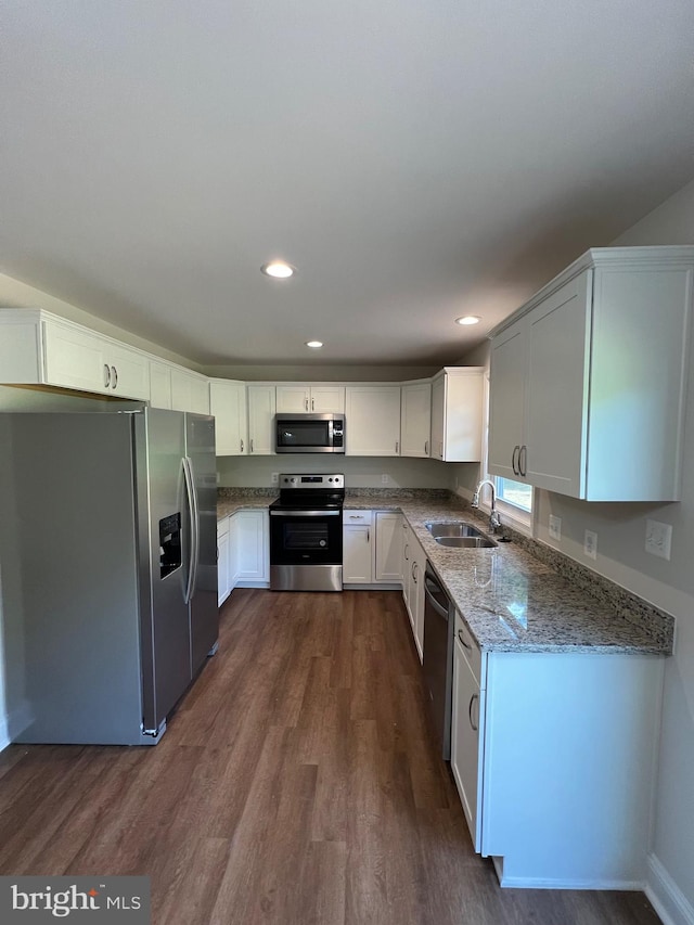 kitchen with white cabinets, sink, dark hardwood / wood-style floors, light stone counters, and stainless steel appliances