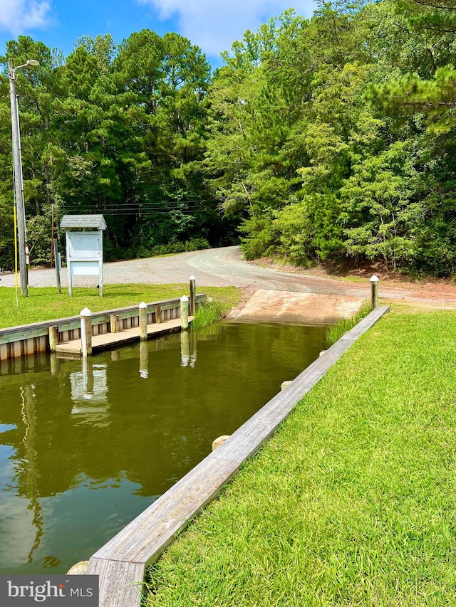 view of dock featuring a lawn and a water view