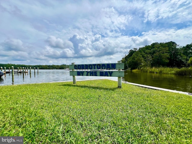 view of dock with a lawn and a water view