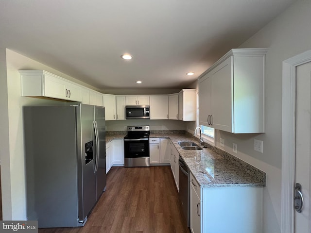 kitchen with sink, dark wood-type flooring, light stone counters, white cabinets, and appliances with stainless steel finishes