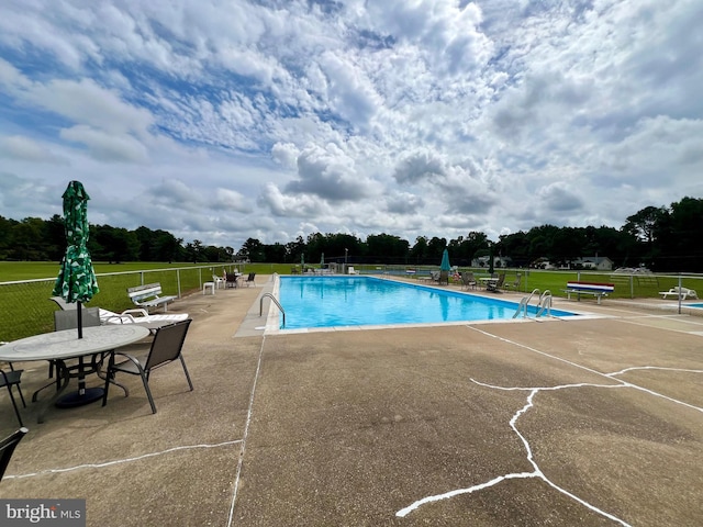 view of pool featuring a patio area and a yard