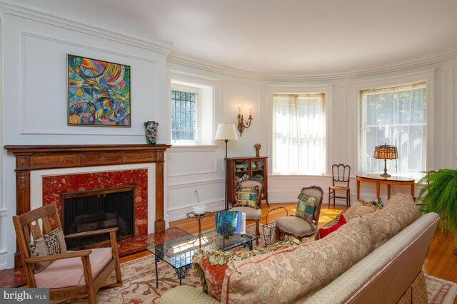 living room with ornamental molding, a high end fireplace, and light hardwood / wood-style flooring