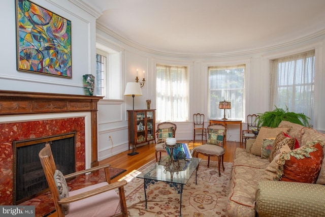 living room featuring light wood-type flooring, a premium fireplace, and crown molding