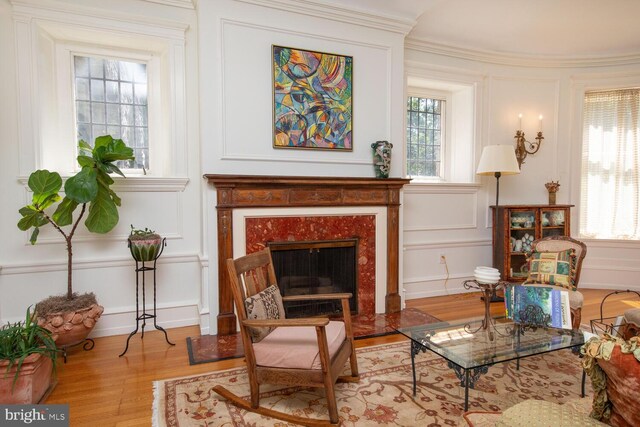 living room featuring a healthy amount of sunlight, light hardwood / wood-style flooring, a fireplace, and crown molding