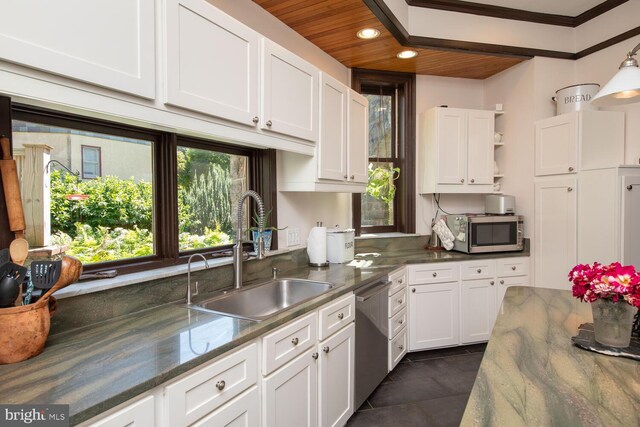 kitchen featuring dark tile patterned flooring, white cabinets, appliances with stainless steel finishes, and sink