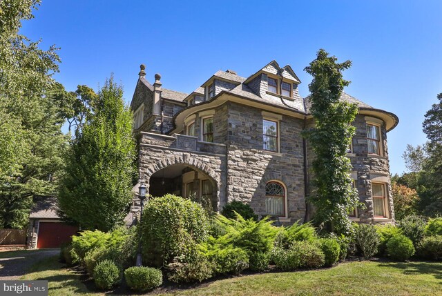 view of front of property featuring a front yard, a balcony, and a garage