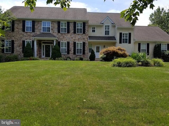 view of front of property featuring a front yard, stone siding, and stucco siding