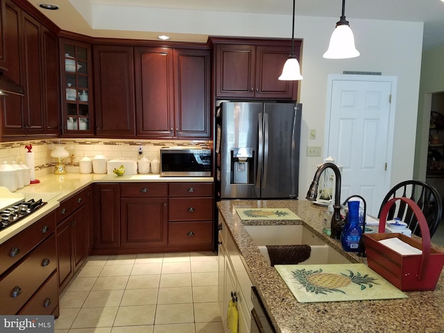 kitchen with stainless steel appliances, sink, light tile patterned floors, hanging light fixtures, and decorative backsplash