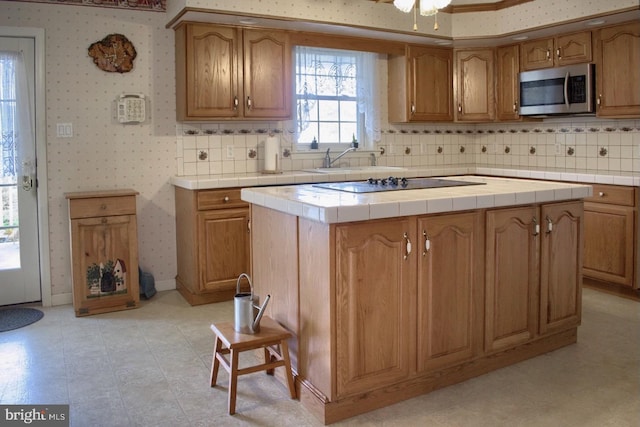 kitchen with a center island, black electric stovetop, tile countertops, and tasteful backsplash