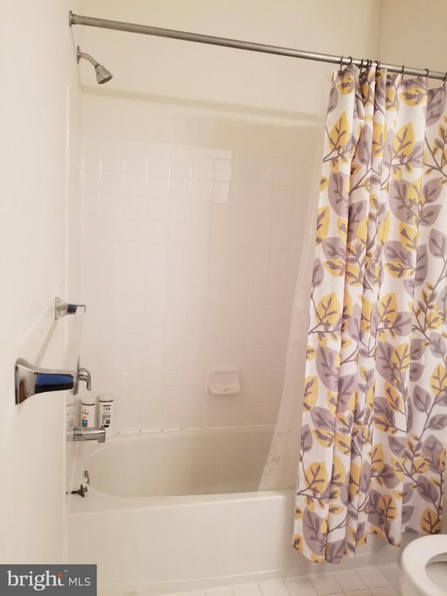 bathroom with toilet, shower / tub combo with curtain, and tile patterned flooring