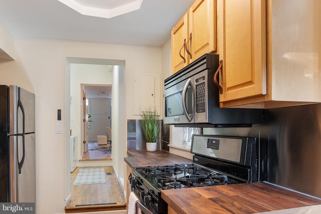 kitchen featuring wood counters, appliances with stainless steel finishes, and light brown cabinets