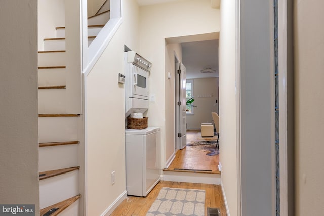 hallway with stacked washer and dryer and light hardwood / wood-style floors