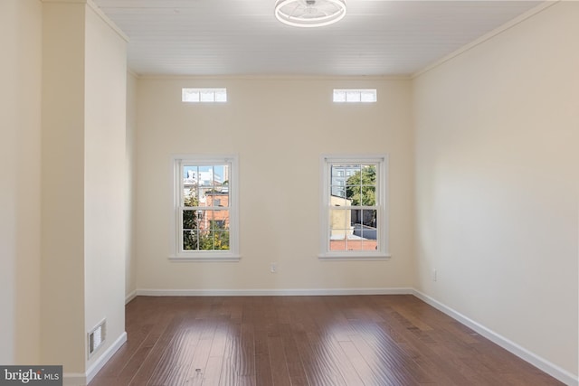 unfurnished room featuring dark hardwood / wood-style flooring, ornamental molding, and a wealth of natural light