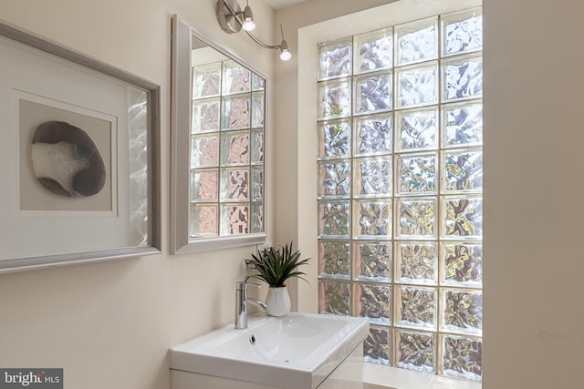 bathroom with an inviting chandelier, a healthy amount of sunlight, and sink