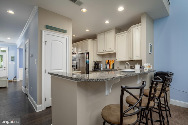 kitchen with visible vents, ornamental molding, stainless steel appliances, a peninsula, and stone counters