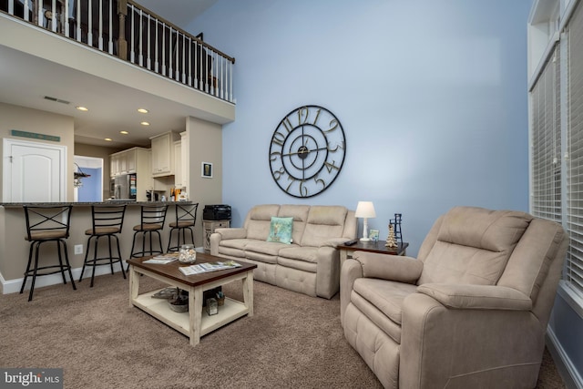 carpeted living room featuring visible vents, recessed lighting, a high ceiling, and baseboards