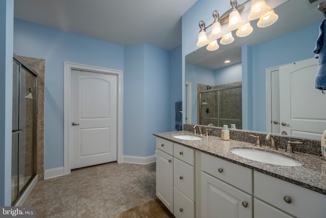 full bath featuring double vanity, baseboards, a stall shower, and a sink