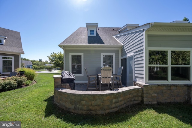 rear view of house featuring a patio area, a lawn, and a shingled roof