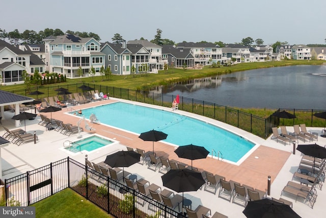 pool with a patio, fence, a residential view, and a water view