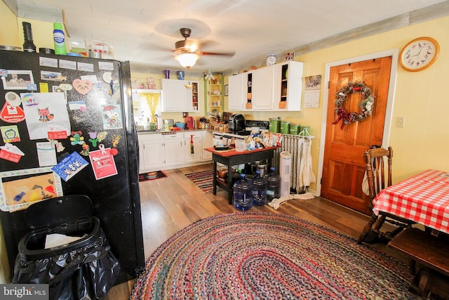 kitchen with light hardwood / wood-style flooring, ceiling fan, white cabinets, and black fridge