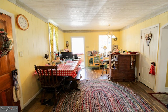 dining space with wood walls, wood-type flooring, and a chandelier