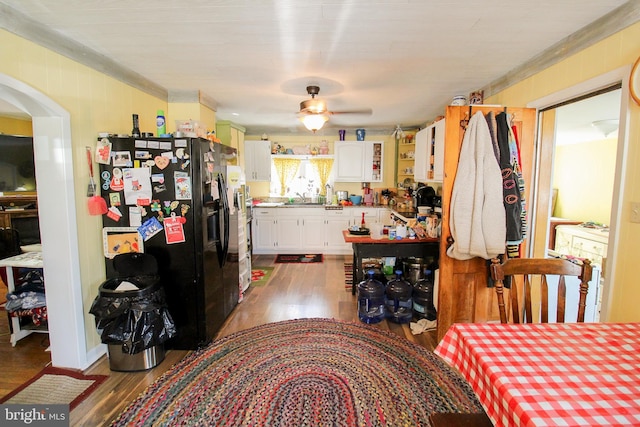 kitchen with white cabinets, ceiling fan, dark hardwood / wood-style floors, and black fridge